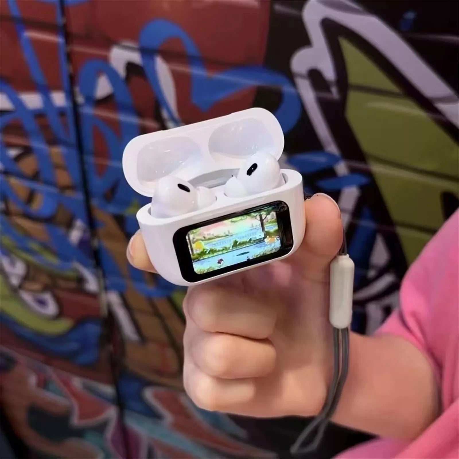 Hand holding a white wireless earbud case with a screen displaying an app interface against a colorful graffiti background.