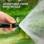 Hand holding an adjustable twist hose nozzle with water spraying, against a green outdoor background.