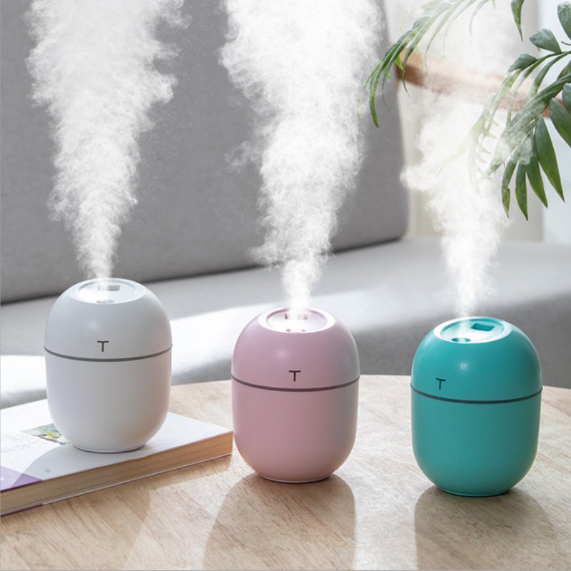 Three colorful humidifiers emitting steam on a wooden surface with a blurred indoor background.