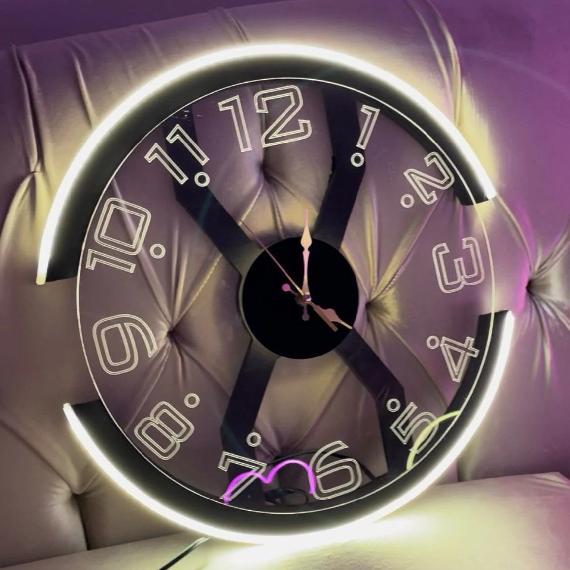 Decorative clock with glowing edge on a purple cushioned surface