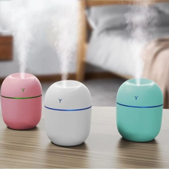 Three colorful humidifiers on a table with steam coming out of them.